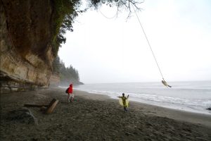 A family enjoys a rope swing on the beach along Oregon's coastline
